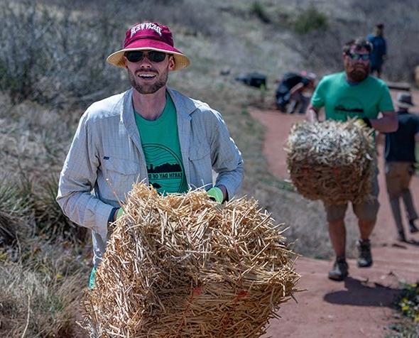 group of people hauling hay bales at Red Rocks 